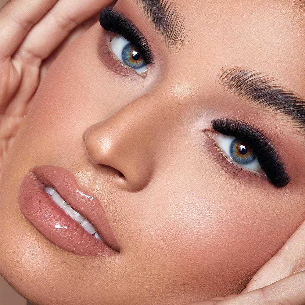 Close-up of a model's face showcasing false eyelashes, long dark eyeliner, defined eyebrows, and glossy nude-pink lipstick. Lash Box LA Australia lash smarter Not HARDER