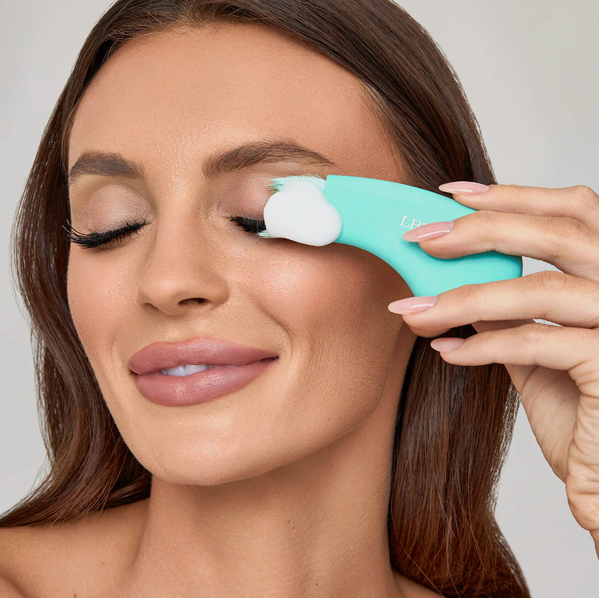 Woman applying a PH balanced Bubble lash shampoo product to her eyelashes with a teal ergonomic cleansing brush applicator. PH Balanced Lash Cleanser Botanical Bubble Lash Shampoo & cleansing brush. 
Size: 180ml
Key Ingredients;Aloe Vera, Calendula, Chamomile, Rosemary, Lavender, Witch Hazel, Willow Bark, pH-balanced formula
Skin Type:All skin types including sensitive
Lash Extension Safe