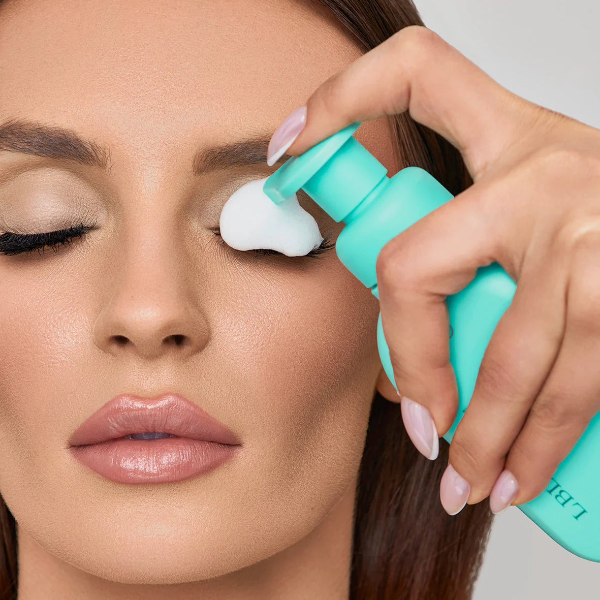 Woman applying PH balanced Botanical bubble lash shampoo to her eyelid and eyelashes from the bottle. Woman applying a PH balanced Bubble lash shampoo product to her eyelashes with a teal ergonomic cleansing brush applicator. PH Balanced Lash Cleanser Botanical Bubble Lash Shampoo & cleansing brush. 
Size: 180ml
Key Ingredients:;Aloe Vera, Calendula, Chamomile, Rosemary, Lavender, Witch Hazel, Willow Bark, pH-balanced formula
